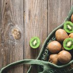 fruits-kiwi-mesh-bag-wooden-background-top-view-rustic-style